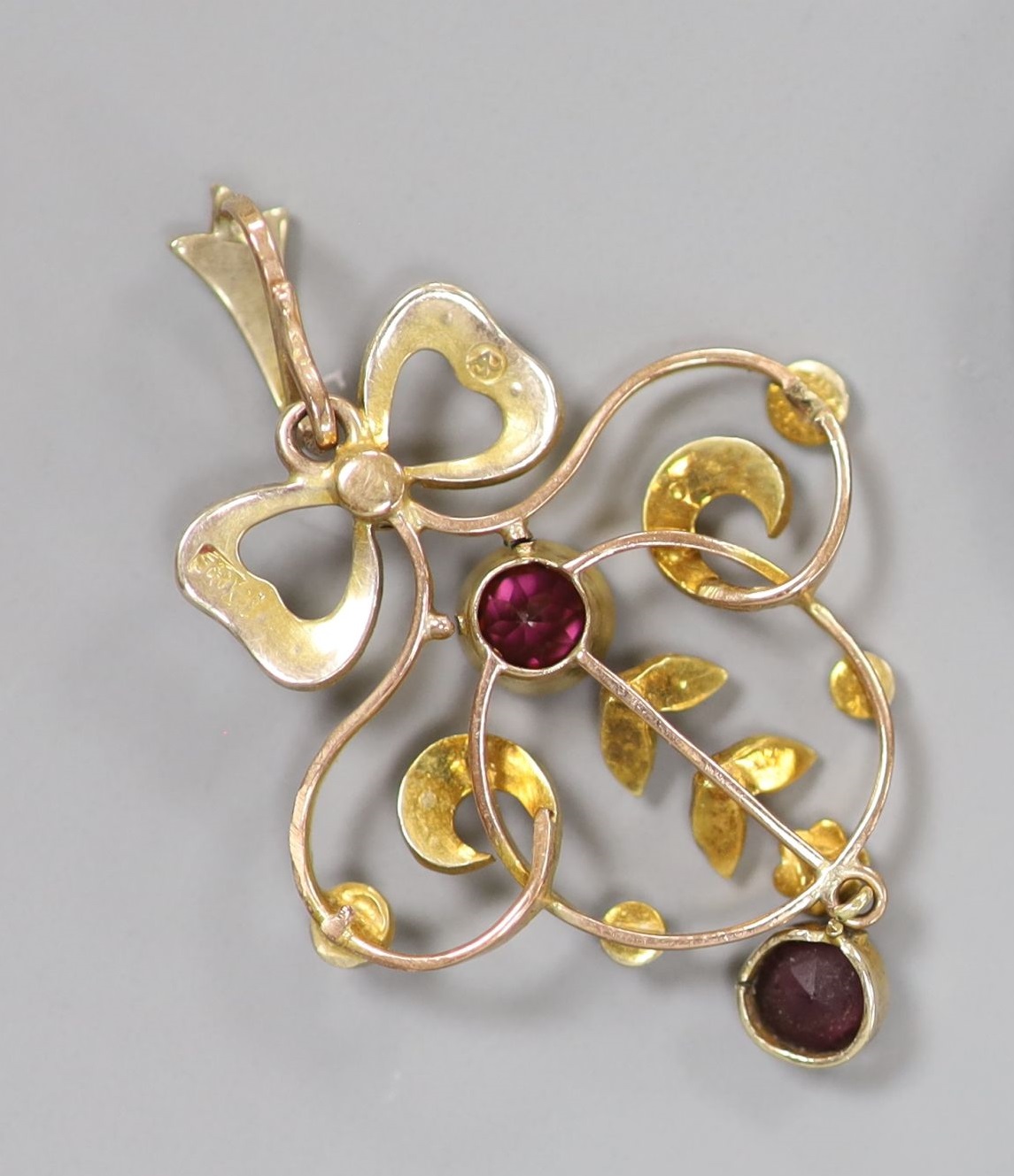 An early 20th century 9ct, garnet and seed pearl set openwork pendant